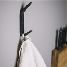 Load image into Gallery viewer, Black metal hook with a white towel on a gray wall
