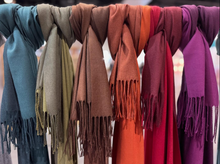 Load image into Gallery viewer, Row of colorful scarves with fringes hanging side by side.
