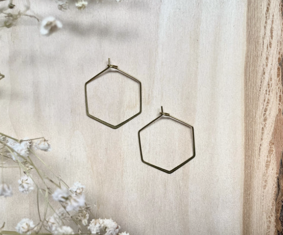 Smooth raw brass hexagon shaped hoop earrings. Displayed on wood with baby's breath