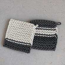 Load image into Gallery viewer, Two knitted pot holders, one white and gray, the other black and gray, on a light gray surface.
