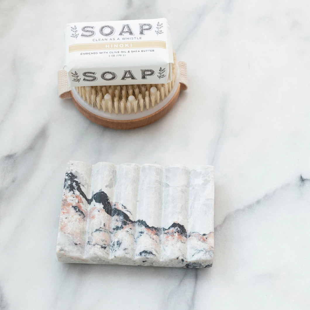 Bar of soap with a brush and packaging on a marble surface