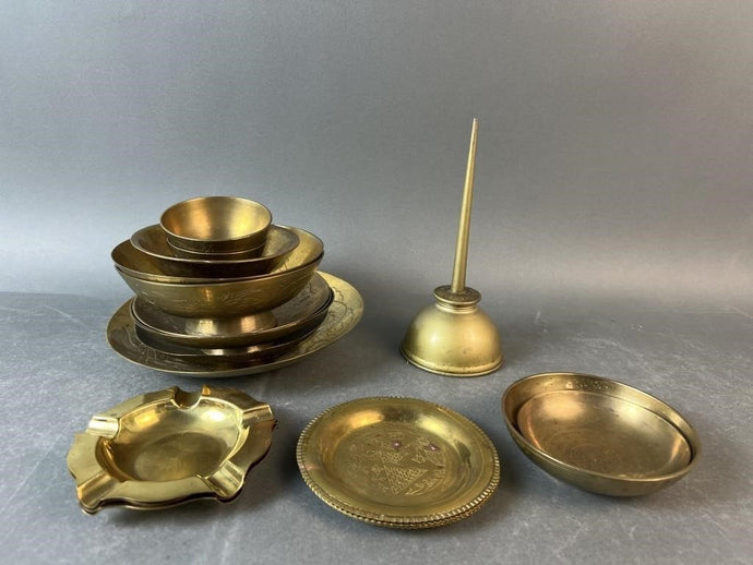 Collection of brass items including bowls, plates on a gray background