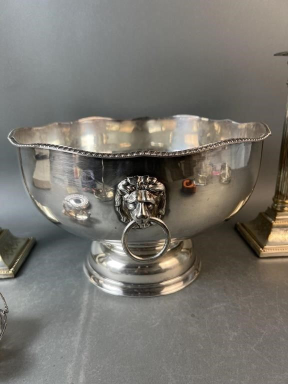 Silver bowl with lion head design on a gray surface
