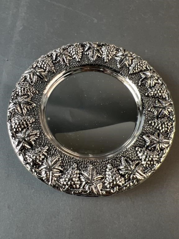 Round metallic mirror with intricate designs on a gray background