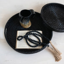Load image into Gallery viewer, Black woven tray with an open book, black beads, and a black pitcher on a light surface.
