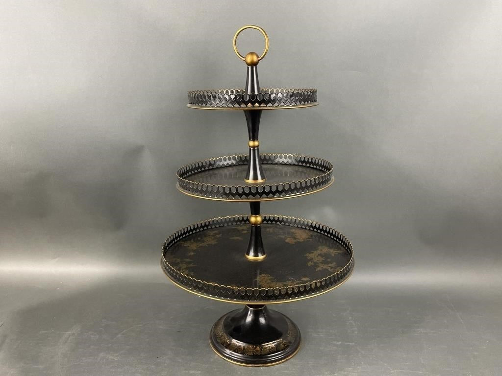 Three-tiered decorative stand with black and gold  and floral design on a gray background
