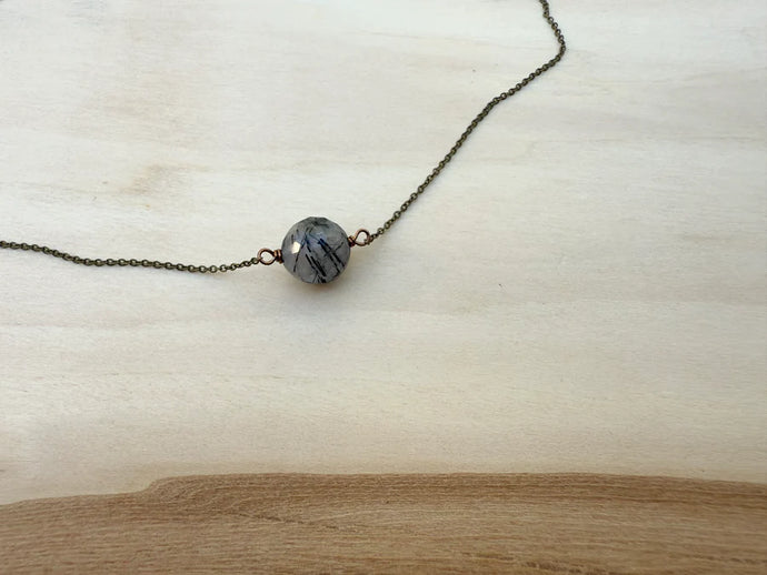 Necklace with a single bead on a light wooden surface