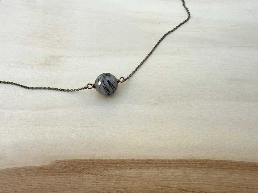 Necklace with a single bead on a light wooden surface