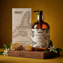 Load image into Gallery viewer, Hand wash bottle and packaging with honeycomb and floral elements on a wooden stand against a yellow background.
