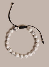 Load image into Gallery viewer, Bracelet with white beads and black cord on a beige background
