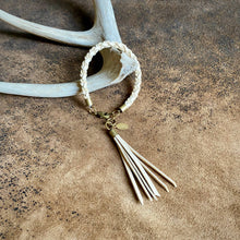 Load image into Gallery viewer, Bracelet with tassel on a textured surface
