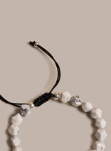 Load image into Gallery viewer, Bracelet with white beads and black cord on a beige background
