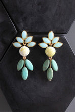 Load image into Gallery viewer, Pair of earrings with light blue floral tops and green leaves on a black background
