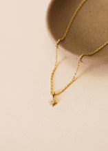 Load image into Gallery viewer, Gold necklace with a small pendant on a beige surface
