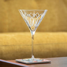 Load image into Gallery viewer, Clear martini glass with geometric design on a wooden coaster against a blurred gold background
