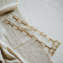 Load image into Gallery viewer, Gold chain necklace on a textured beige fabric background
