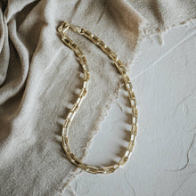 Load image into Gallery viewer, Gold chain necklace on a textured beige fabric background
