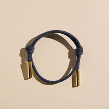 Load image into Gallery viewer, Navy blue bracelet with gold clasps on a beige background
