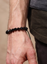 Load image into Gallery viewer, Close-up of a wrist wearing a black beaded bracelet against a neutral background
