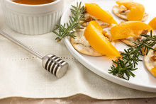 Load image into Gallery viewer, Plate of food with crackers and peaches, accompanied by a honey dipper and small bowl on a textured surface.
