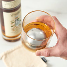 Load image into Gallery viewer, A person holding a glass of whiskey with a chilling stainless steel sphere floating in it
