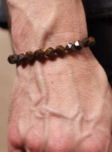Load image into Gallery viewer, A close-up of a person's wrist wearing a dark brown faceted bead bracelet.
