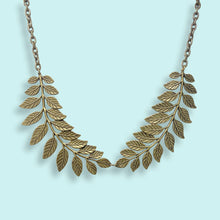 Load image into Gallery viewer, Gold leaf necklace on a light blue background
