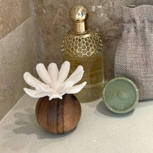 Load image into Gallery viewer, A decorative perfume bottle with a gold honeycomb-patterned neck and a white flower-shaped diffuser on a wooden base, styled next to a small green soap bar and a burlap drawstring bag on a stone surface.
