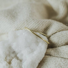 Load image into Gallery viewer, Gold bracelet on a textured beige fabric background
