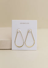 Load image into Gallery viewer, Gold hoop earrings on a Jaxkelly branded card against a beige background
