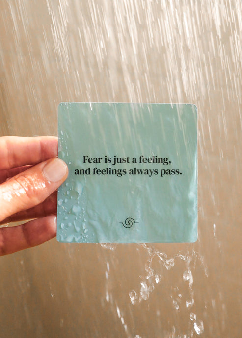 Hand holding a card with a motivational quote against a water background