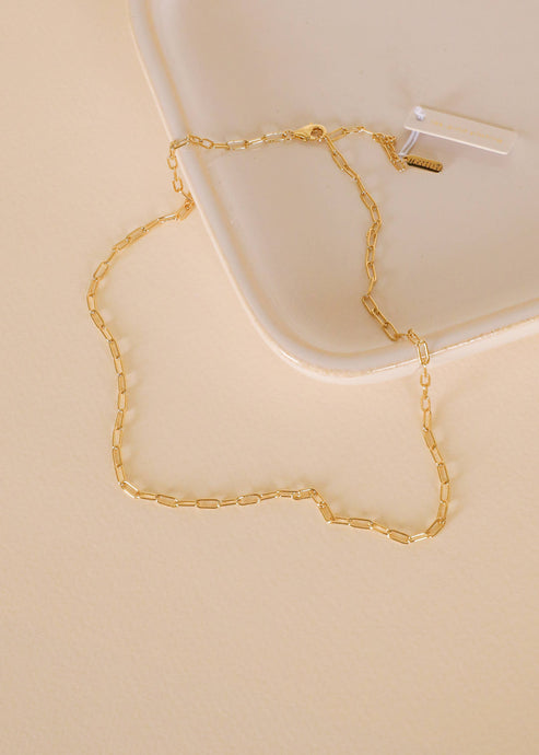 Gold chain necklace on a beige surface