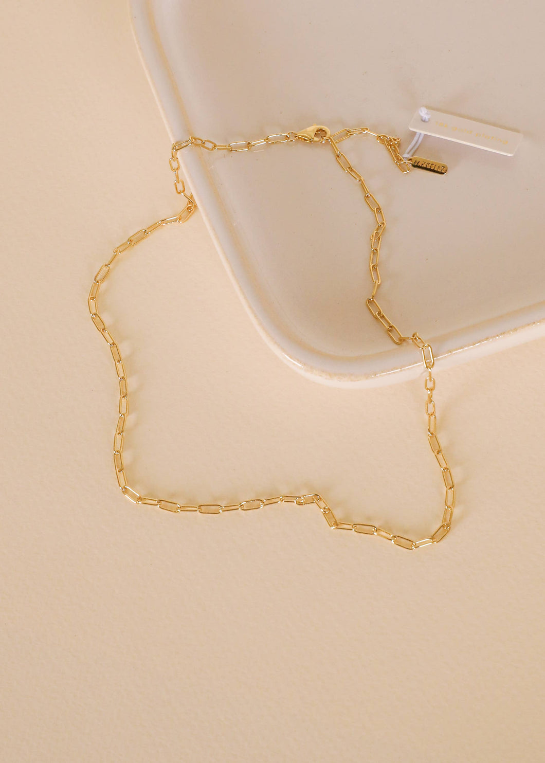 Gold chain necklace on a beige surface